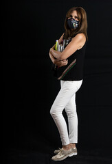beautiful woman with protective mask on black background with books in hand