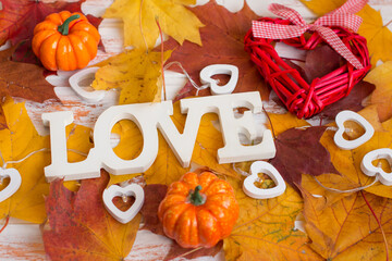 The word love on an autumn background with yellow leaves. Autumn still life