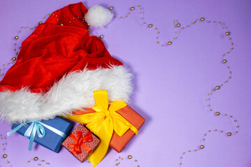 Christmas presents and Santa Claus hat on colourful background. New Year's flatlay.