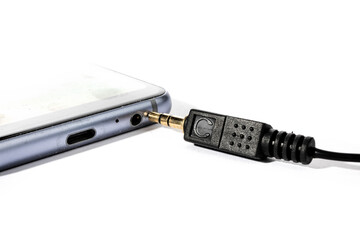 macro closeup of a headphone plug and audio jack on a cell phone