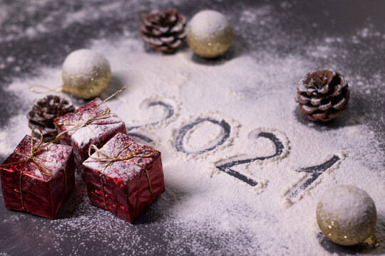 Christmas decorations, decor elements in the snow. golden balls and cones. Finger-drawn '2021' in the snow. Christmas mood. Flatly photo.