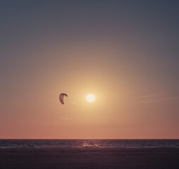 Beautiful september sunset with a kitesurfer fliying. Golden hour. By the sea. Beach landscape. 