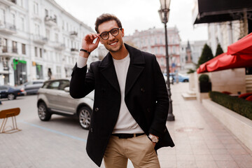 Young man wearing  autumn  clothes  walking on  the street. Stylish  guy with modern hairstyle in urban background.