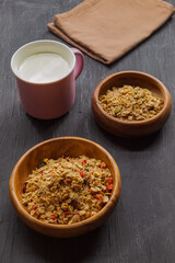 Milk in a purple mug and multi-glaf muesli on a black background