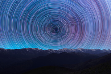Long exposure night landscape. Beautiful mountains and. colorful star trails on the sky. Night time...