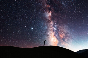 Beautiful starry sky with bright milky way galaxy. Night landscape . Person silhouette stands on...