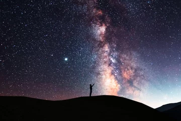 Foto op Plexiglas Mooie sterrenhemel met heldere Melkweg. Nacht landschap. Persoonssilhouet staat op de heuvel en kijkt naar de sterrenhemel. © Inga Av