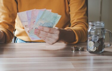 Young beautiful asian woman holding money banknotes in home, concept finance business investment property.