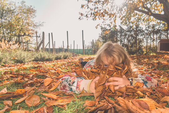 child lying in colorful autumnal leaves