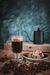 Black coffee in glass cup on wooden table and cookies 