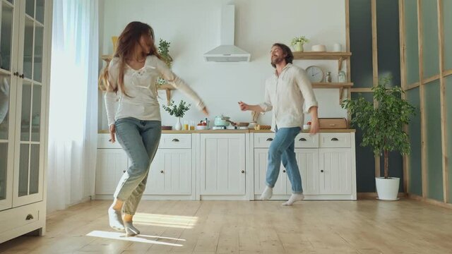 Lovely Couple Having a Fun Together While Dancing at the Bright Kitchen. Couple Dancing in Cozy Modern Kitchen at Home. Man and Woman Enjoy Spending Time Together.