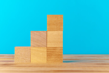 Stacked wooden blocks on wooden desk against blue background