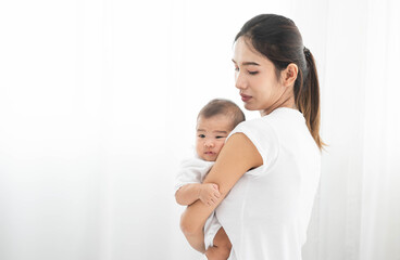Pretty asian woman holding a newborn baby in her arms. Happy family. Laughing mother lifting her adorable infant baby son on white. 