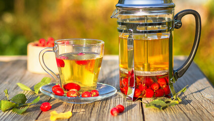 A cup of hot rosehip tea on a wooden table in the autumn garden.Close-up