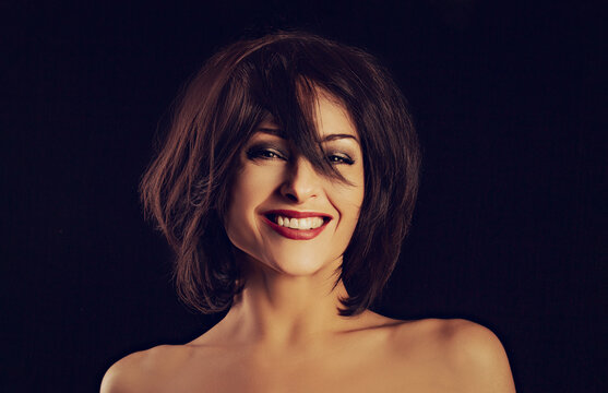 Beautiful happy laughing bright makeup woman shaking her black short hair on black background. Closeup portrait