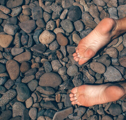 woman legs on sea pebbles
