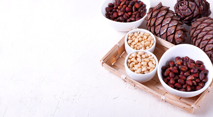 Shelled and unshelled pine nuts and pine cones on the white table. Copy space