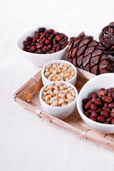 Shelled and unshelled pine nuts and pine cones on the white table. Copy space
