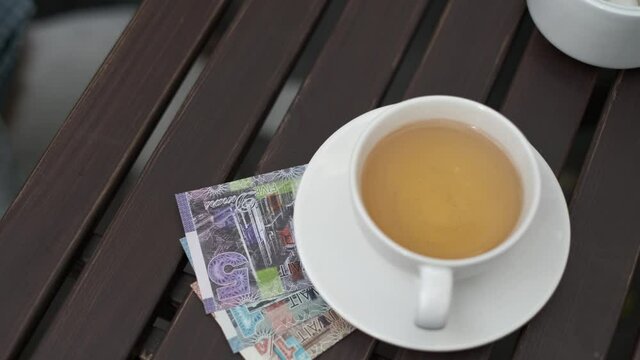 Man put Kuwaiti dinars to pay for coffee in a street cafe