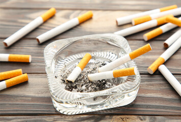 Cigarette butts with ash in ashtray on grey wooden table