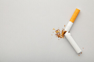 Broken cigarette on grey background with copy space.