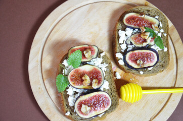 Sandwiches with ricotta, fresh figs, walnuts and honey. Canape or crostini with toasted baguette, cheese, jam, Delicious appetizer, ideal as an aperitif. Selective focus