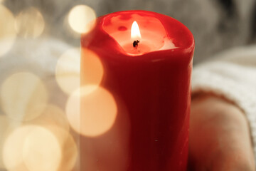Red burning Christmas candle in female hands