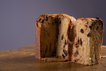 Panettone with chocolate chips on rustic wood with gray background, selective focus.