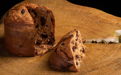 Panettone with chocolate chips on rustic wood with black background, selective focus.