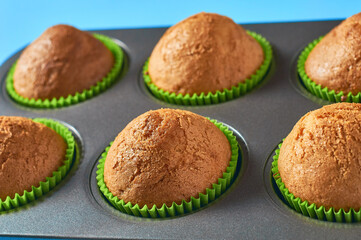 Fluffy muffins in metal brazier on blue background