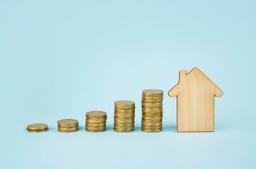 Business concept. Wooden house and coins on a blue background. Concept of family insurance, home purchase. Copy space.