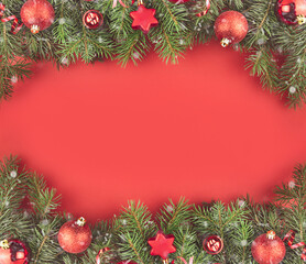Fototapeta na wymiar Christmas frame from red Christmas balls on branches of a Christmas tree on a red background. Christmas and New Year theme. Flat lay, top view.