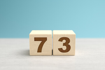 Wooden toy blocks forming the number 73.