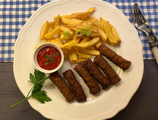 Grilled ground meat skewers with french fries and ketchup. A type of kebab.