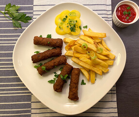 Grilled ground meat skewers with french fries and ketchup. A type of kebab.