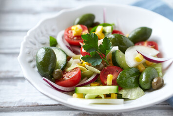 Healthy Salad with Green Olives, Baby Spinach, Cucumber, Cherry Tomatoes and Capers. Bright background. Close up.