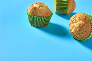 One fluffy muffin in green paper mold on blue background. Copy space