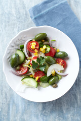 Healthy Salad with Green Olives, Baby Spinach, Cucumber, Cherry Tomatoes and Capers. Bright wooden background. Top view. Close up.