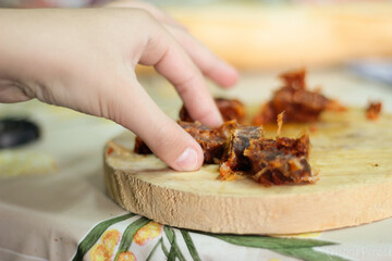 Mano cogiendo un trozo de chorizo sobre una tabla de madera