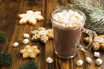 Hot cocoa or chocolate drink with marshmallow in the glass cup on the wooden background