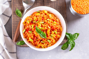 Homemade vegan lentil soup with vegetables and basil, light background, top view. Indian vegetarian cuisine.