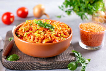 Stewed red lentils with vegetables in a ceramic bowl on a light background. Bright, tasty, spicy food