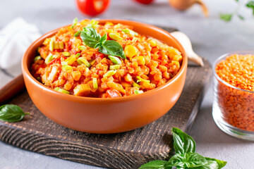 Vegetarian lentil stew in a bowl with basil on light background. Traditional turkish or arabic lentil and vegetable soup, healthy vegan food.