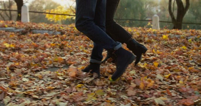 Low view of couple having romantic walk in autumn park with golden leaves