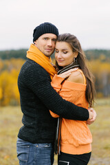 Fototapeta premium A young pretty woman hugs her boyfriend in the fall outdoors. Lovers walk in the Park. Cute lovers in the Park. The family concept. happy couple.