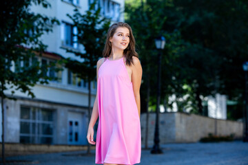 Beautiful european girl in summer dress walking on the street. Sexy young woman in red dress.