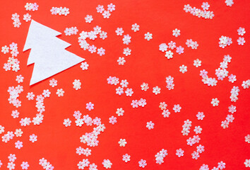 Christmas background, shiny white sequins scattered on a bright red background, white figure of a Christmas tree