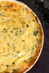 Cheese pie with vegetables, vegetarian food. Dark background, vertical photo.