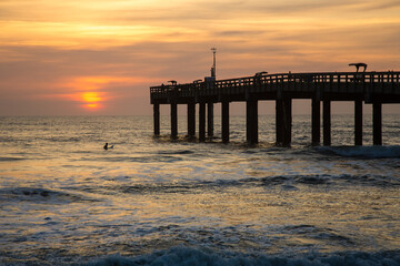 Fototapeta na wymiar Sunrise through a fishing pier at the beach at St Augustine, Florida.