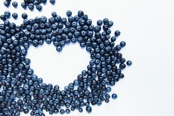 Heart shape made of fresh Blueberries on white background. Healthy food, summer berries. Minimal food concept. Flatlay. Selective focus. Copy space.